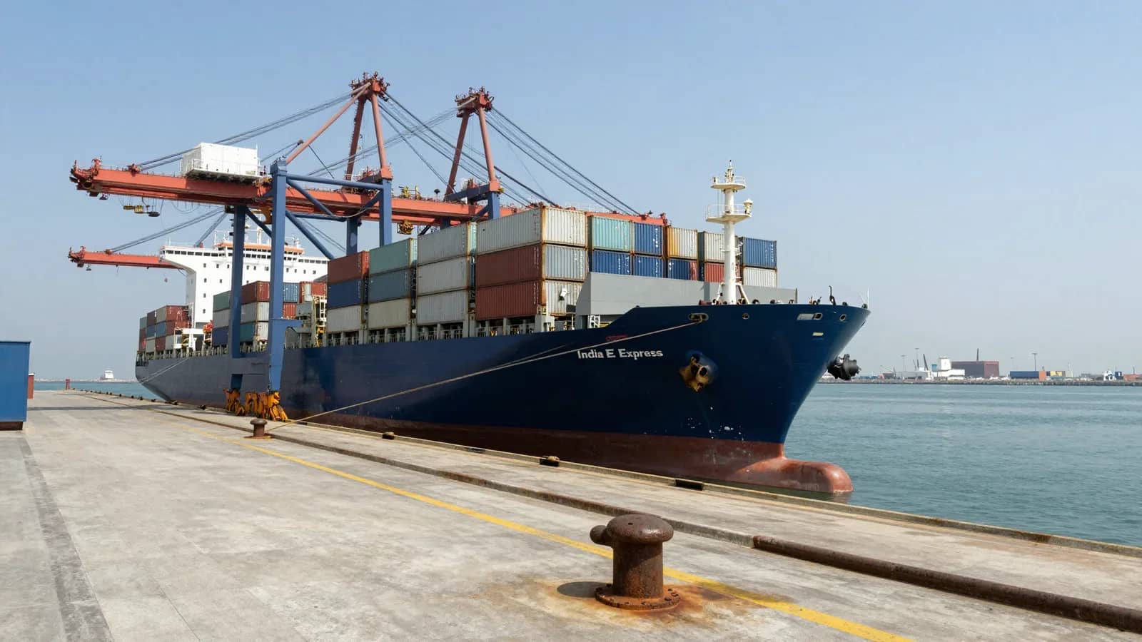Buque de carga portacontenedores atracado en un puerto comercial bajo un cielo despejado.