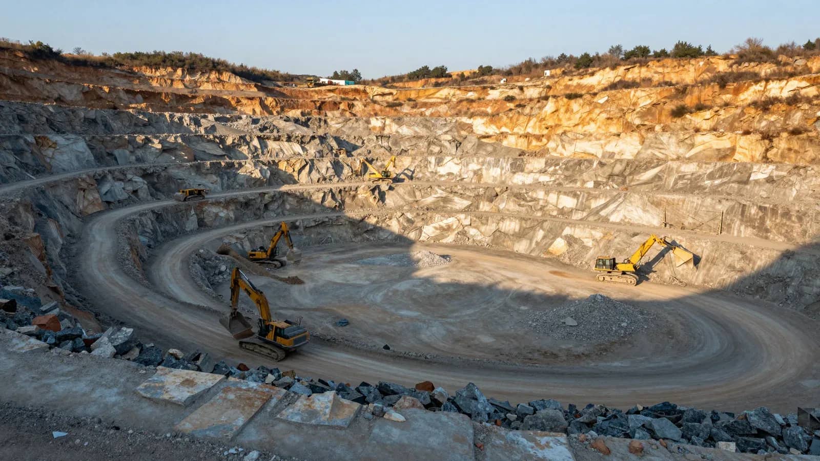 Cantera minera a cielo abierto con maquinaria pesada excavando en las paredes de tierra y roca estratificada