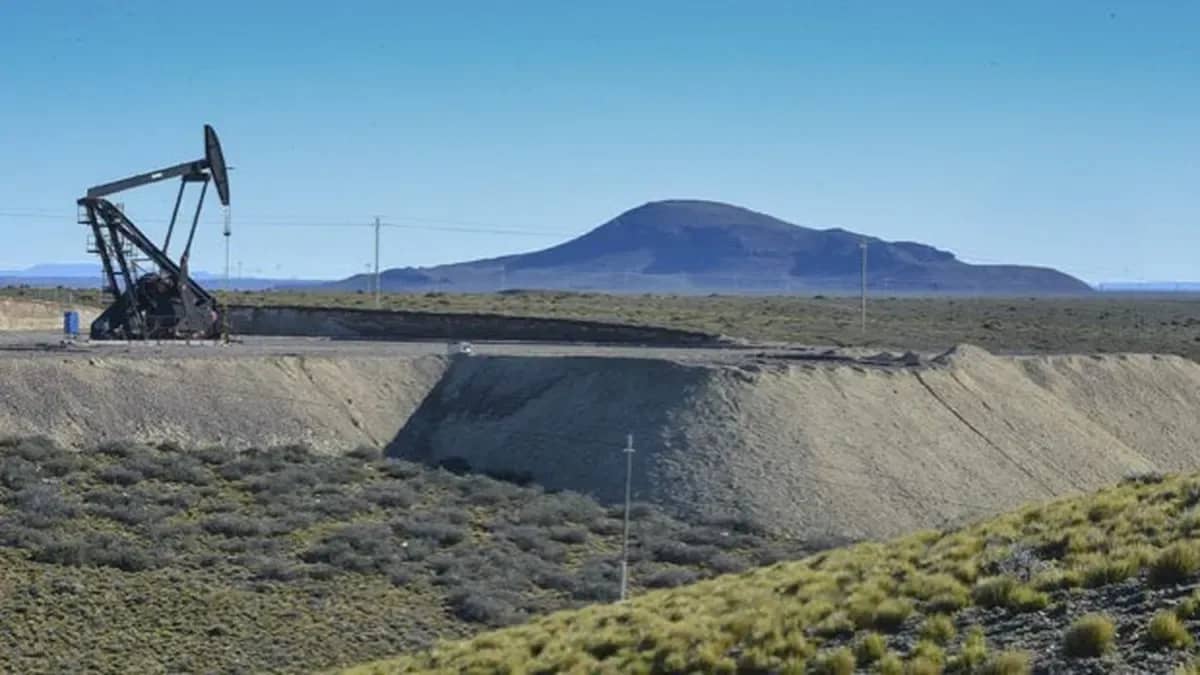Unidad de bombeo de petróleo en operación en yacimiento desértico con montaña al fondo