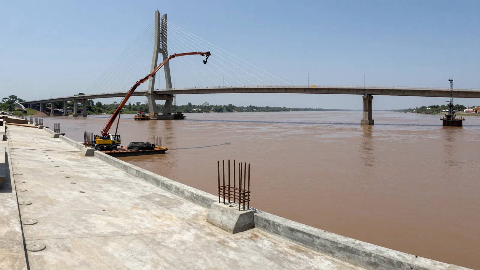 Vista general de la construcción del puente sobre el río Paraguay con grúa y pilotes.